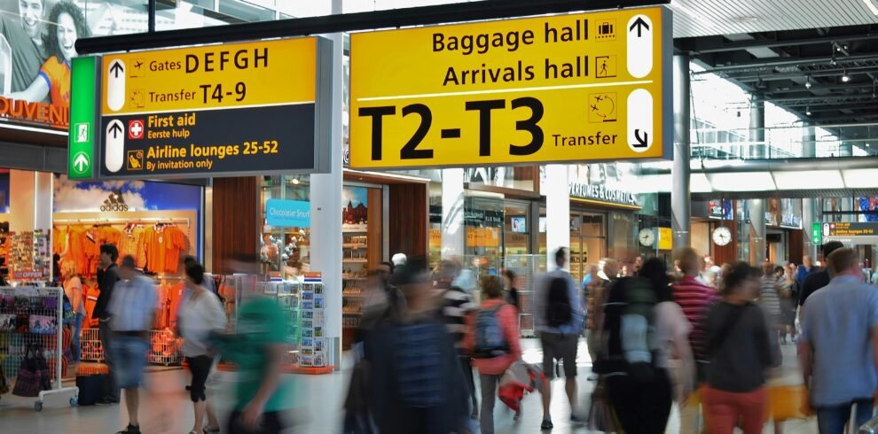 Crowded airport with motion blur and clear signage indicating baggage and arrival halls.